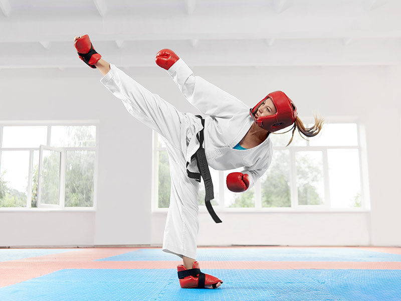 Chica practicando taekwondo con protecciones